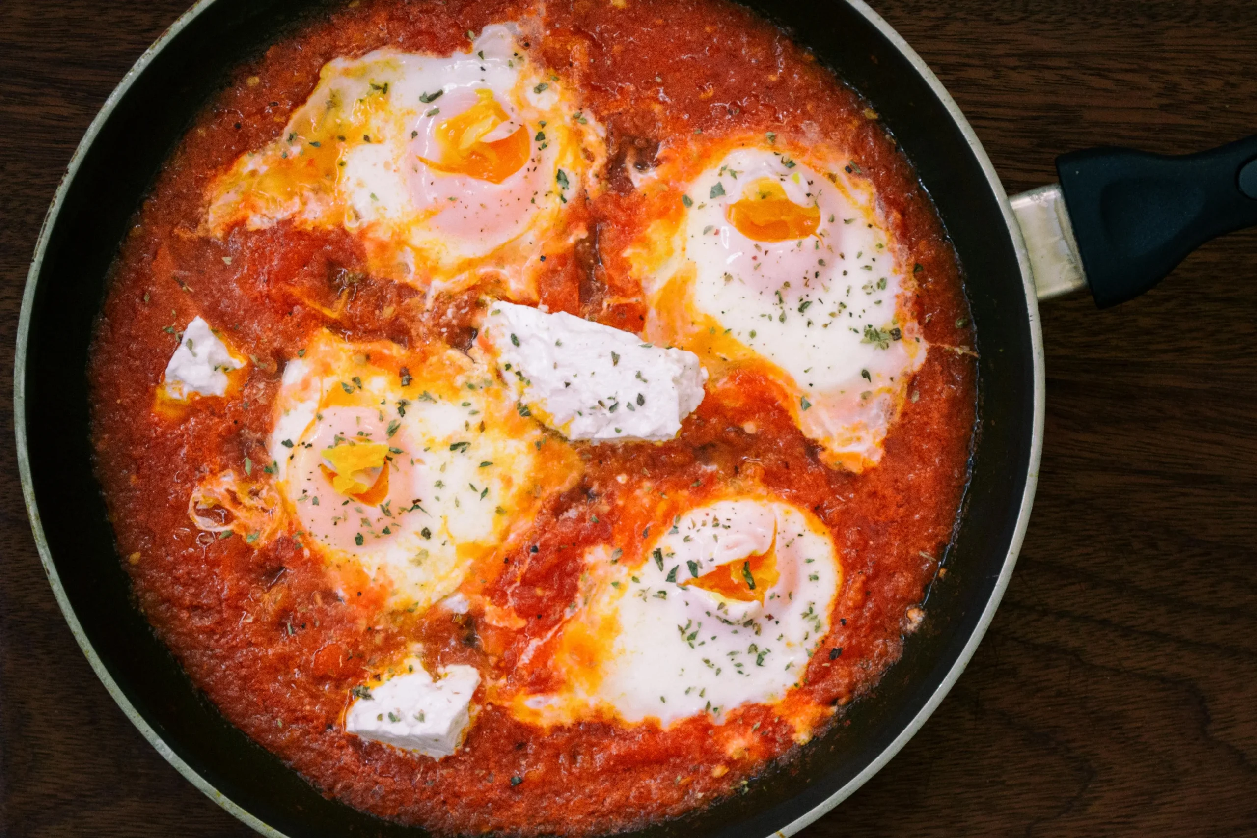 A sizzling pan of Feta-infused Shakshuka with poached eggs.