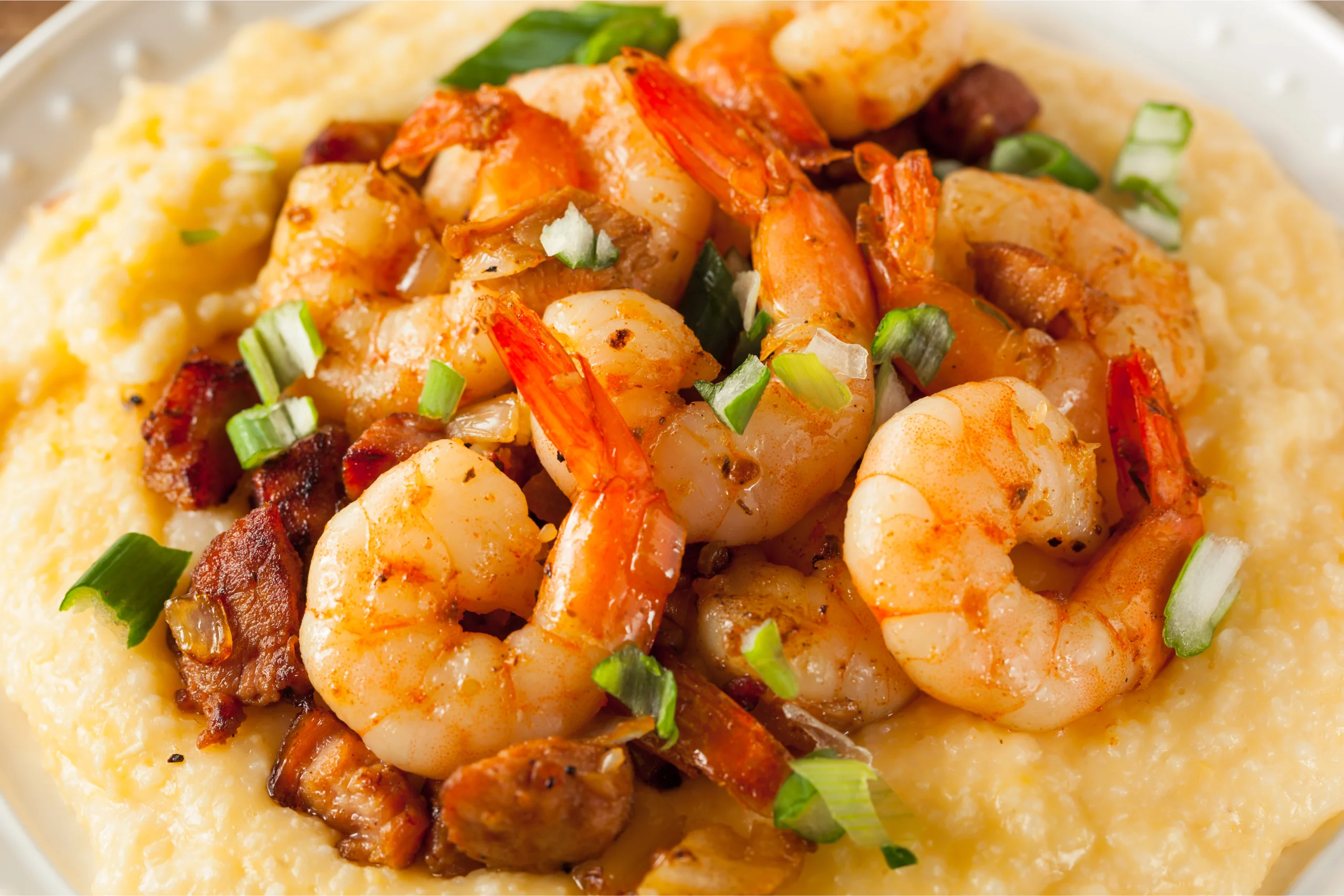 Shrimp and grits with lemon-garlic sauce, garnished with parsley and lemon wedges.