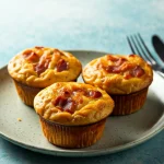 Fluffy egg-stuffed bacon and cheese muffins on a cooling rack.